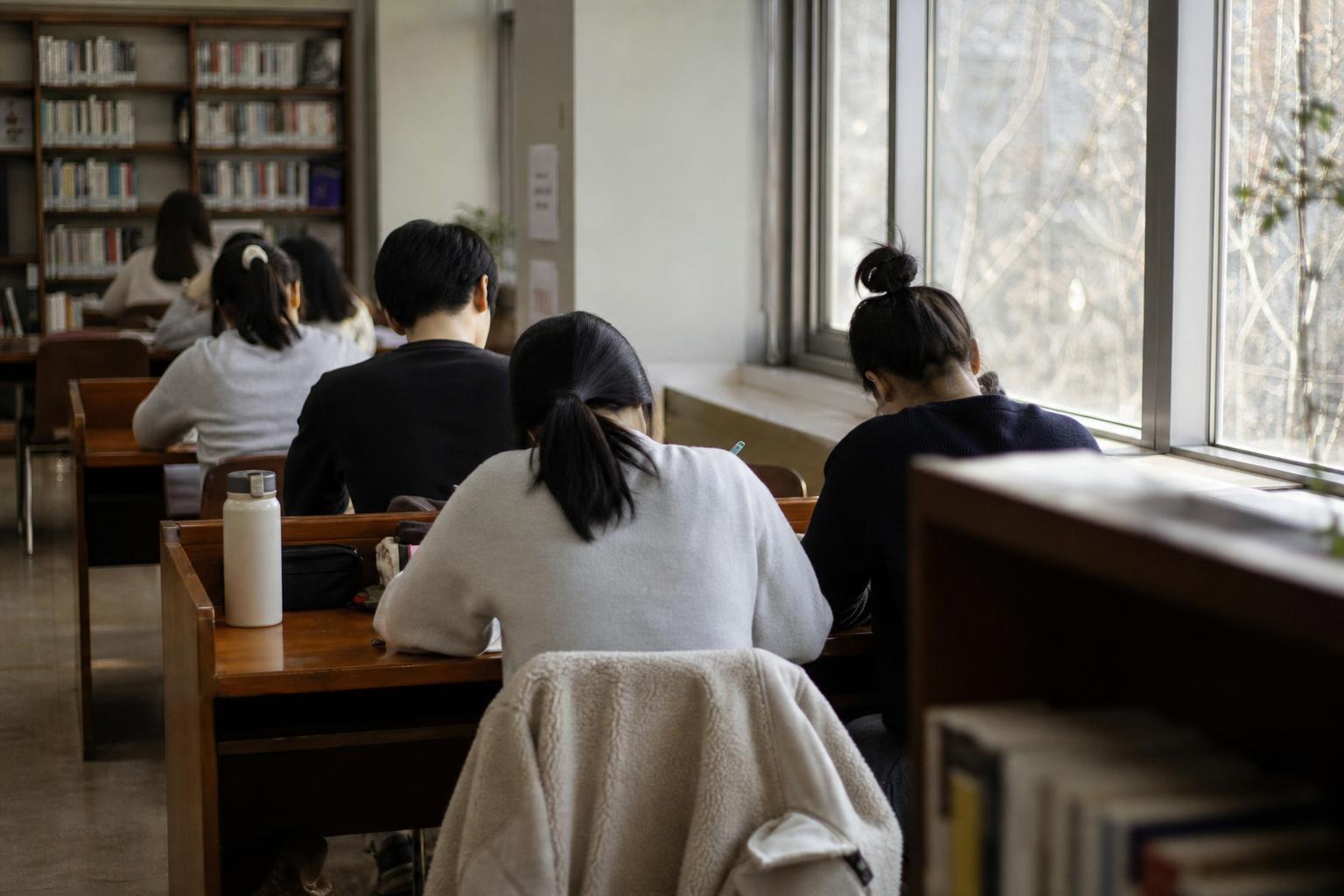 한국의 도서관 열람실에서 책상에 앉아 공부하는 사람들의 뒷모습