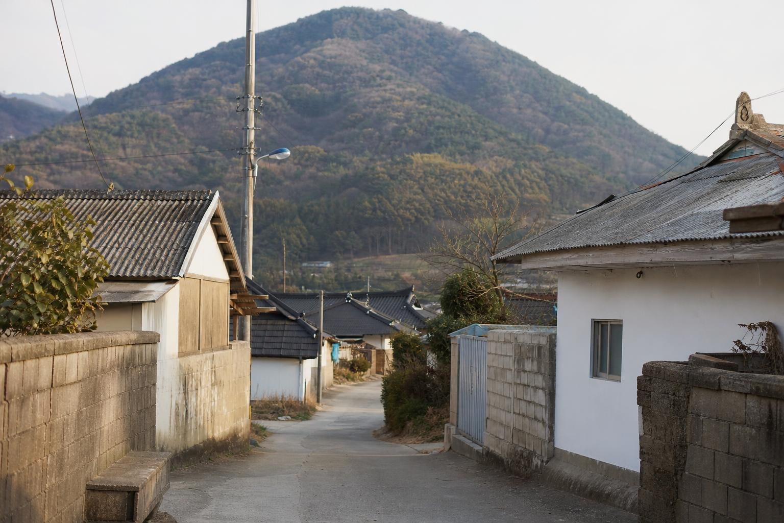 산자락 아래 조용한 한국 시골 마을의 골목과 낮은 지붕들