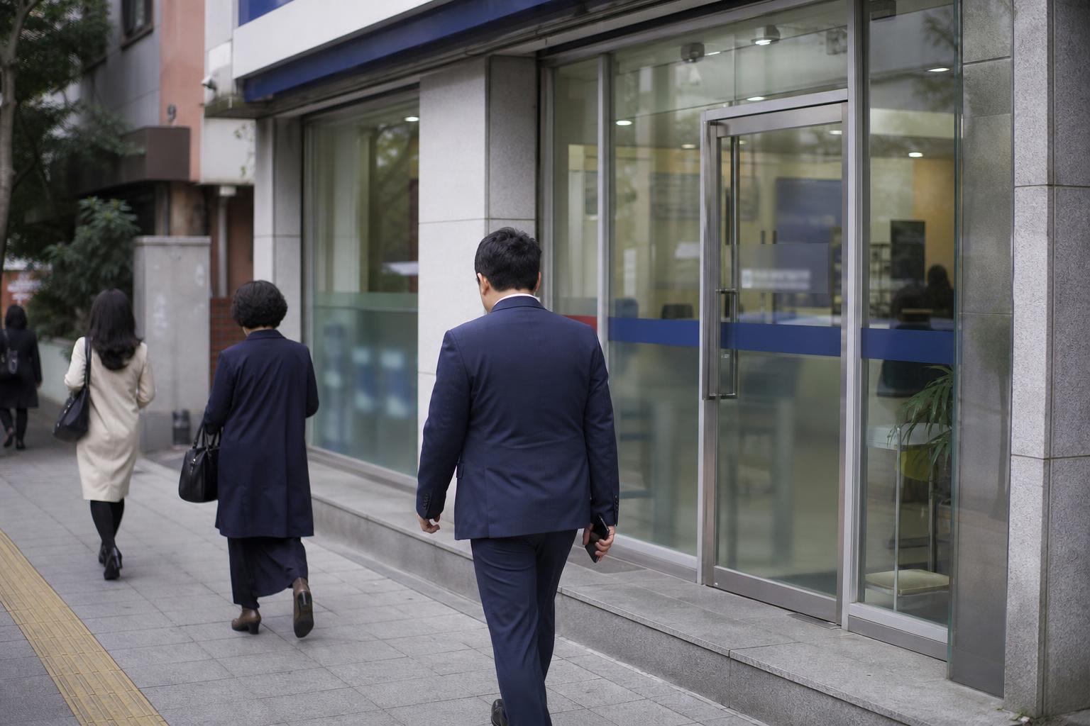 이른 아침 한국 은행 지점 앞을 지나가는 사람들의 뒷모습