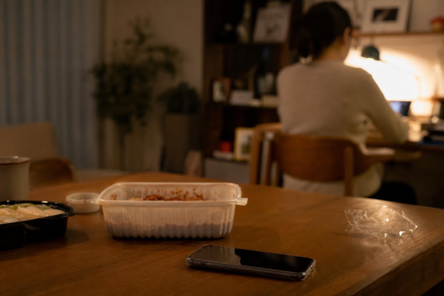 저녁 식탁 위에 놓인 스마트폰과 배달 음식 포장