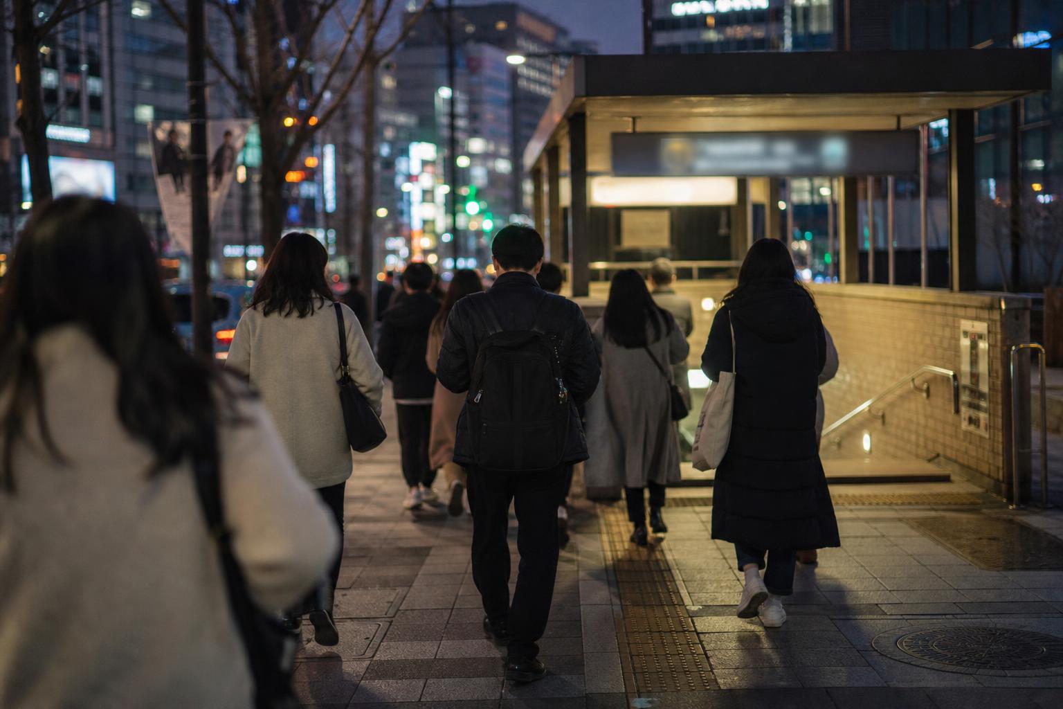 가을 저녁 한국 도시의 지하철역 계단을 내려가는 사람들의 뒷모습