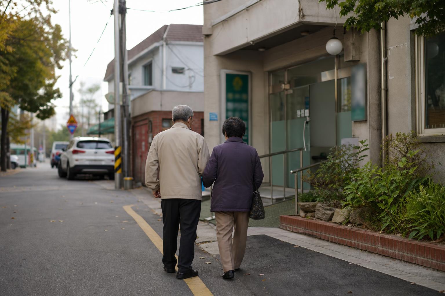 한국 동네 병원 앞 보도를 노인 부부가 걷는 가을 아침 모습